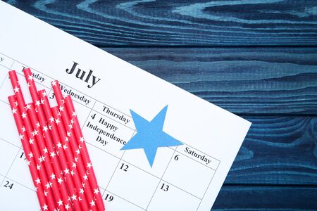 Text Happy Independence Day in calendar with red straws on blue wooden tableの写真素材