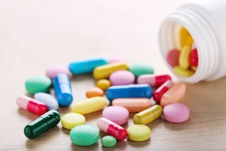 Colorful pills and bottle on wooden tableの写真素材