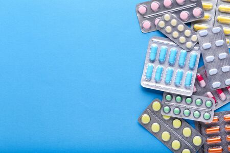 Colorful pills in blisters on blue background