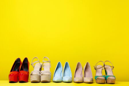 Different high heel shoes on yellow backgroundの写真素材
