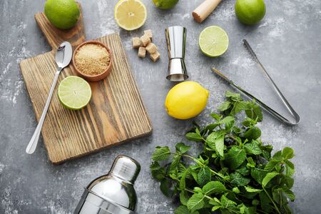 Barman equipments with limes, lemons and mint leafs on grey wooden tableの写真素材