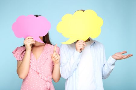 Happy young couple with paper speech bubbles on blue backgroundの写真素材