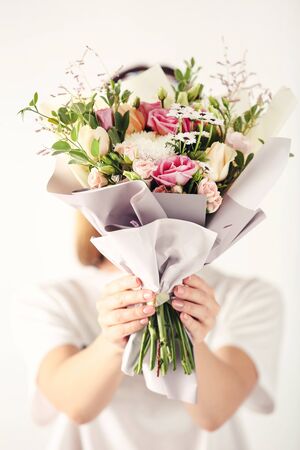 Female hands holding beautiful flower bouquet on white backgroundの写真素材
