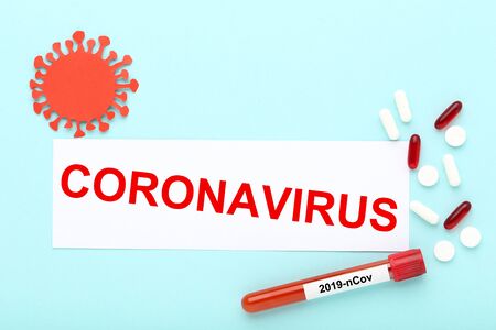 Text Coronavirus with pills and test tube with blood on blue backgroundの写真素材