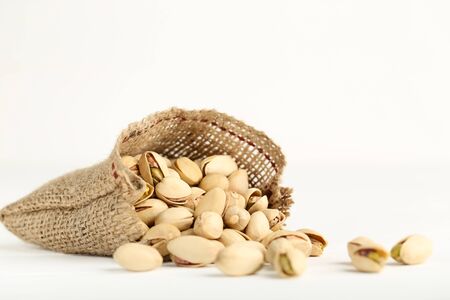 Tasty pistachios in sack on white backgroundの写真素材