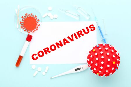 Text Coronavirus with pills, thermometer, test tube and syringe on blue backgroundの写真素材