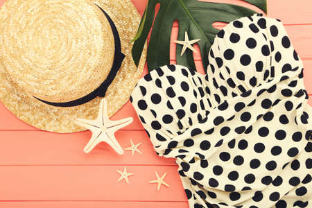 Fashion swimsuit with straw hat, monstera leaf and starfishes on wooden tableの写真素材