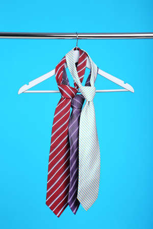 Neckties hanging on wooden hanger on blue backgroundの写真素材