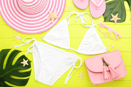 Fashion swimsuit with straw hat, monstera leafs, handbag and starfishes on green wooden tableの写真素材