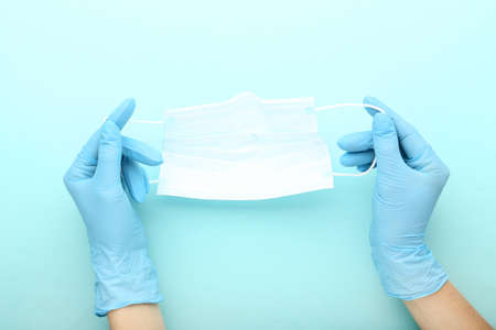 Medicine face mask and female hands in gloves on blue background