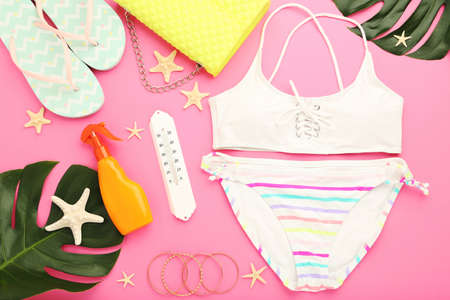Fashion swimsuit with flip flops, monstera leafs and starfishes on pink background