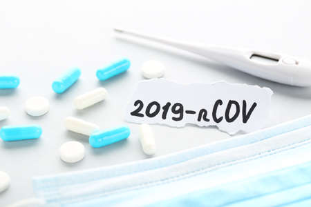 Text 2019-nCov with pills, medicine mask and thermometer on gray backgroundの写真素材