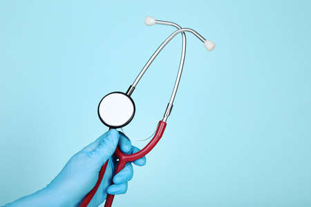 Doctor hand in glove holding stethoscope on blue background