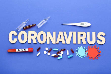 Text Coronavirus with pills, thermometer, ampoules and test tube on blue backgroundの写真素材