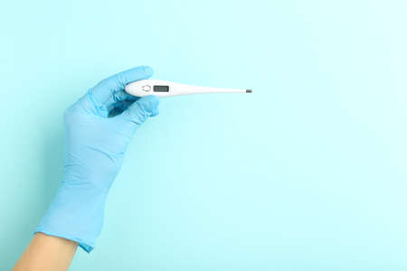 Doctor holding thermometer on blue background