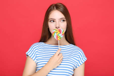 Beautiful girl with lollipop on red backgroundの写真素材