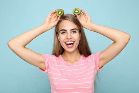 Young girl holding kiwi fruit on blue backgroundの写真素材