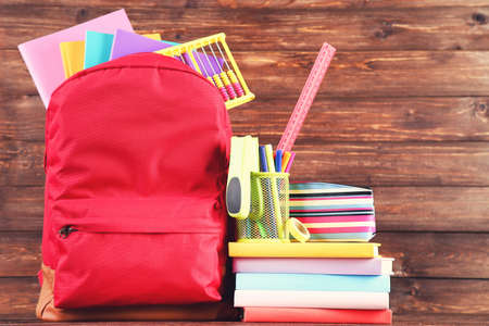 Backpack with school supplies on brown wooden backgroundの写真素材