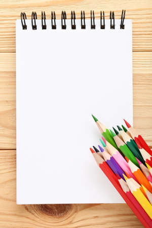 Colored pencils with notebook on brown wooden tableの写真素材