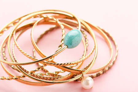 Golden bracelets on pink background