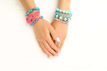 Female hands with beautiful bracelets on white wooden backgroundの写真素材