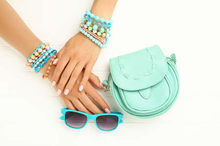Female hands with bracelets, sunglasses and handbag on white wooden backgroundの写真素材