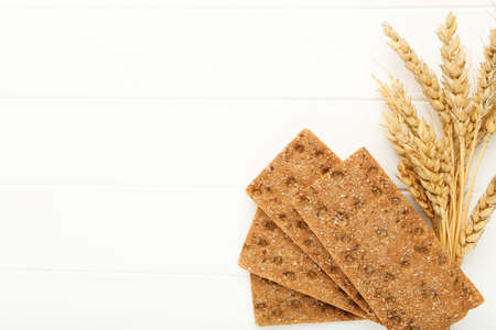 Rye crispbread with wheat ears on white wooden tableの写真素材