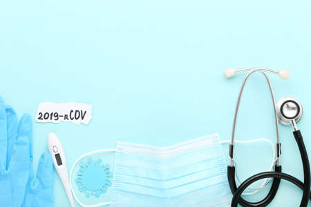 Text 2019-nCov with medicine mask, stethoscope, thermometer and pair of gloves on blue background