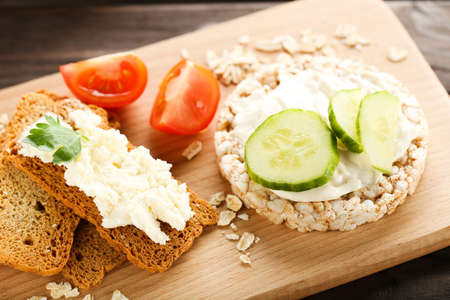 Crispbread with cream cheese and vegetables on wooden boardの写真素材