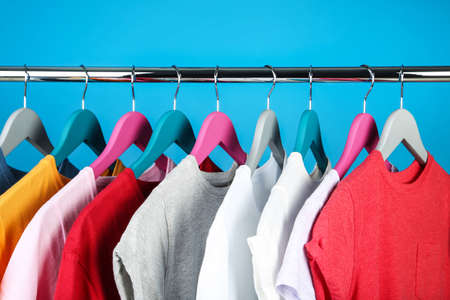 Wooden hangers with clothes on blue backgroundの写真素材