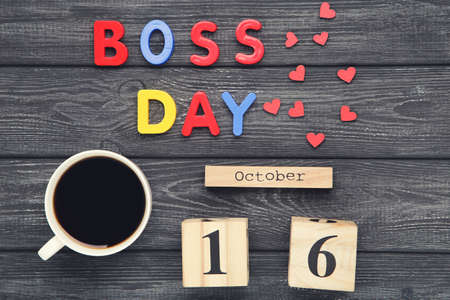 Colorful inscription Boss Day with cup of coffee and calendar on black wooden backgroundの写真素材