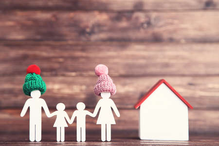Wooden family figures in hats and house on brown backgroundの写真素材