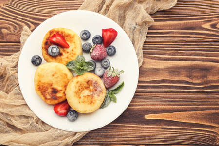Sweet cheese pancakes with berries and mint leafs on wooden tableの写真素材