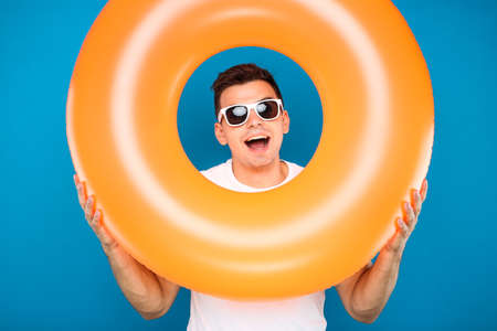 Young man with inflatable ring on blue backgroundの写真素材