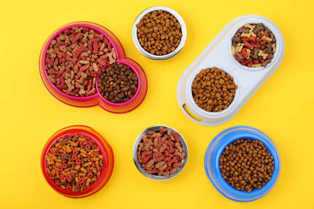 Dry pet food in bowls on yellow backgroundの写真素材