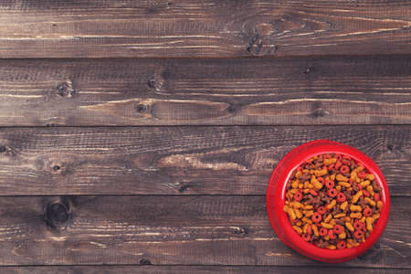 Dry pet food in bowl on brown wooden tableの写真素材