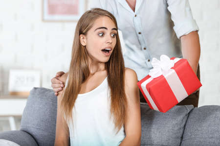 Surprised woman getting gift box from boyfriendの写真素材