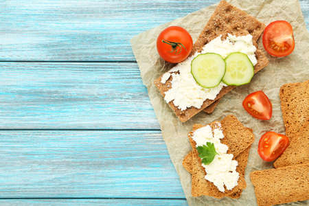 Crispbread with cream cheese and vegetables on blue wooden tableの写真素材