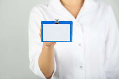 Female hand showing blank white bagde on gray backgroundの写真素材