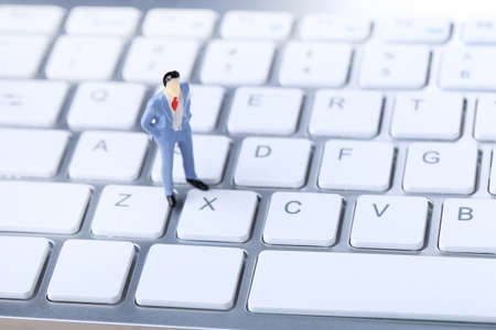 Miniature people on white computer keyboard