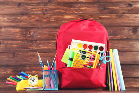 Backpack with school supplies on brown wooden backgroundの写真素材