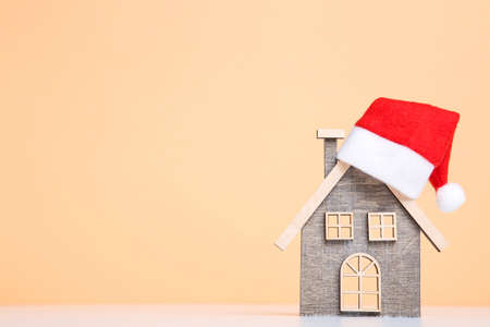 Wooden house model with santa hat on beige backgroundの写真素材