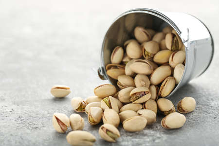 Tasty pistachios in bucket on gray backgroundの写真素材