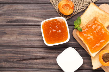 Toast with apricot jam and cream in bowl on wooden tableの写真素材