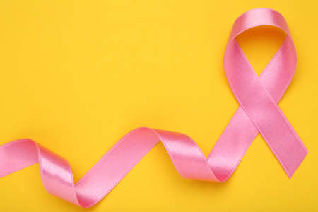 Cancer concept. Pink ribbon on yellow backgroundの写真素材