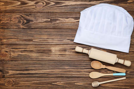 Chef hat with cooking cutlery on wooden backgroundの写真素材