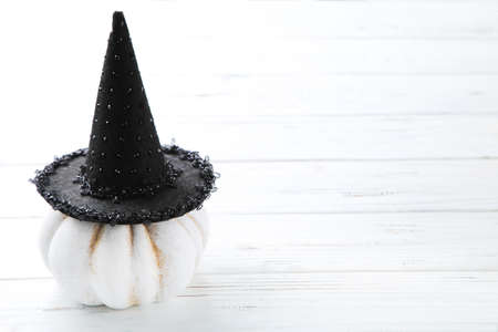 Halloween pumpkin with black hat on wooden background