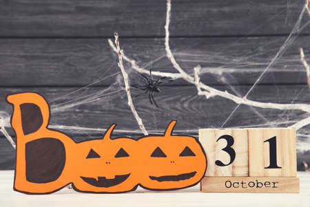 Halloween concept. Wooden calendar with word Boo, tree branches and spiders on black backgroundの写真素材