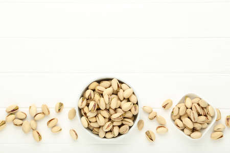 Pistachios in bowls on white wooden tableの写真素材
