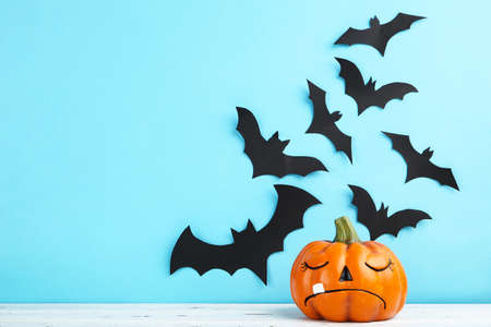 Halloween paper bats with orange pumpkin on blue background